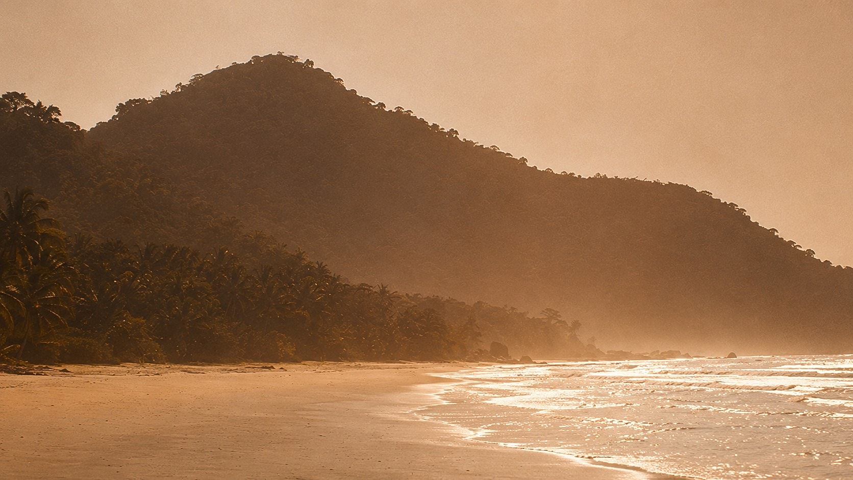 Sunset over a serene beach and mountains.