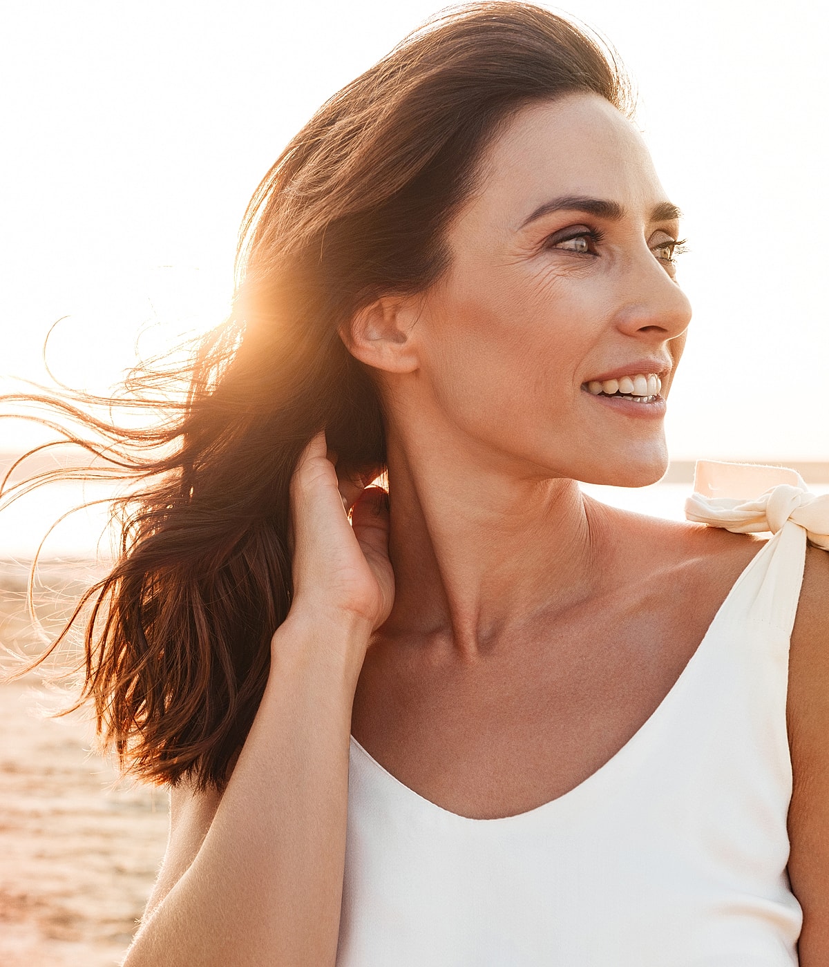 Woman with flowing hair by sunset beach.